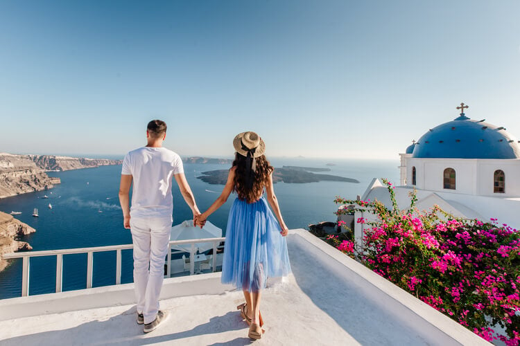 A couple holding hands looking out over Santorini
