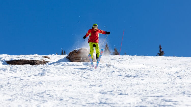 A skier jumping off a rock at Vail