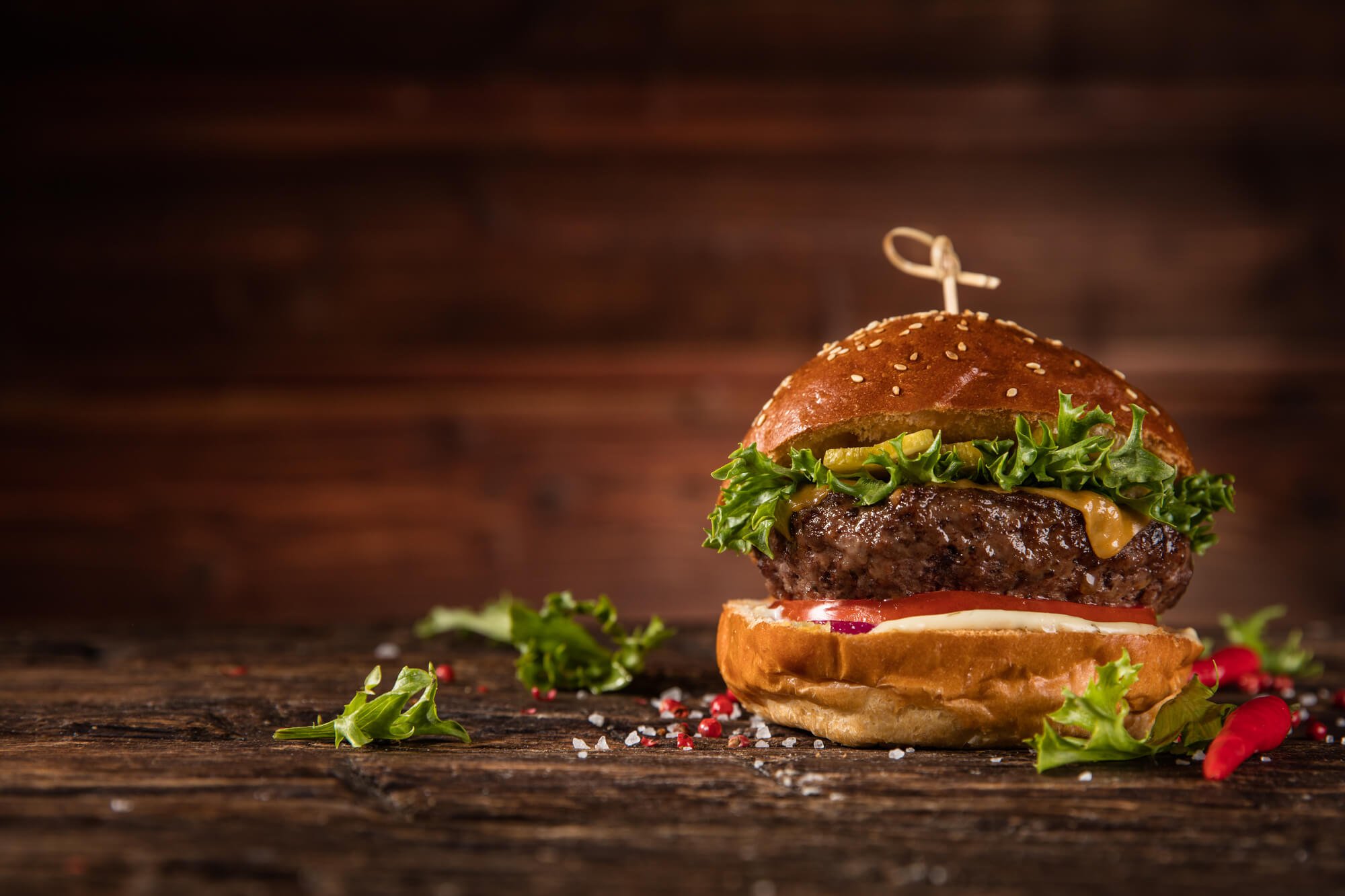 A burger on a wooden board against a dark background