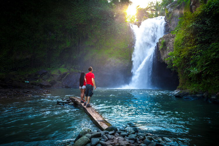 A couple standing in front of a Bali waterfall