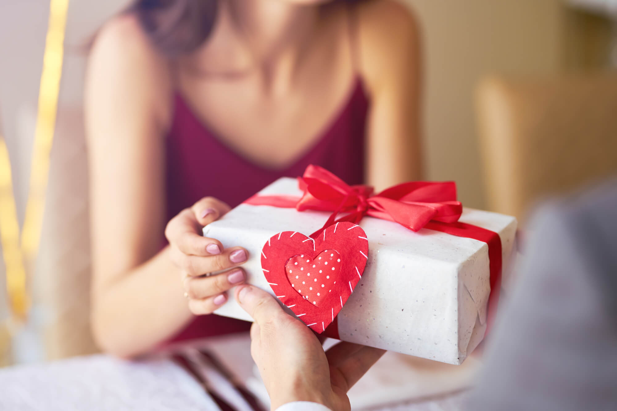A person being handed a present wrapped in a red bow