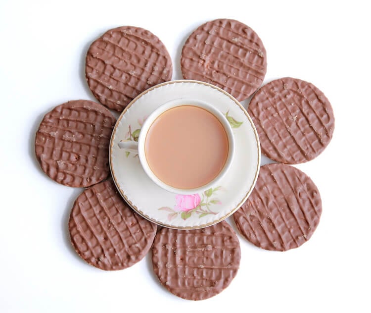 A circle of chocolate digestive biscuits around a cup of tea