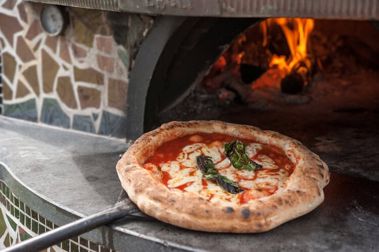 A Margherita pizza coming out of the oven