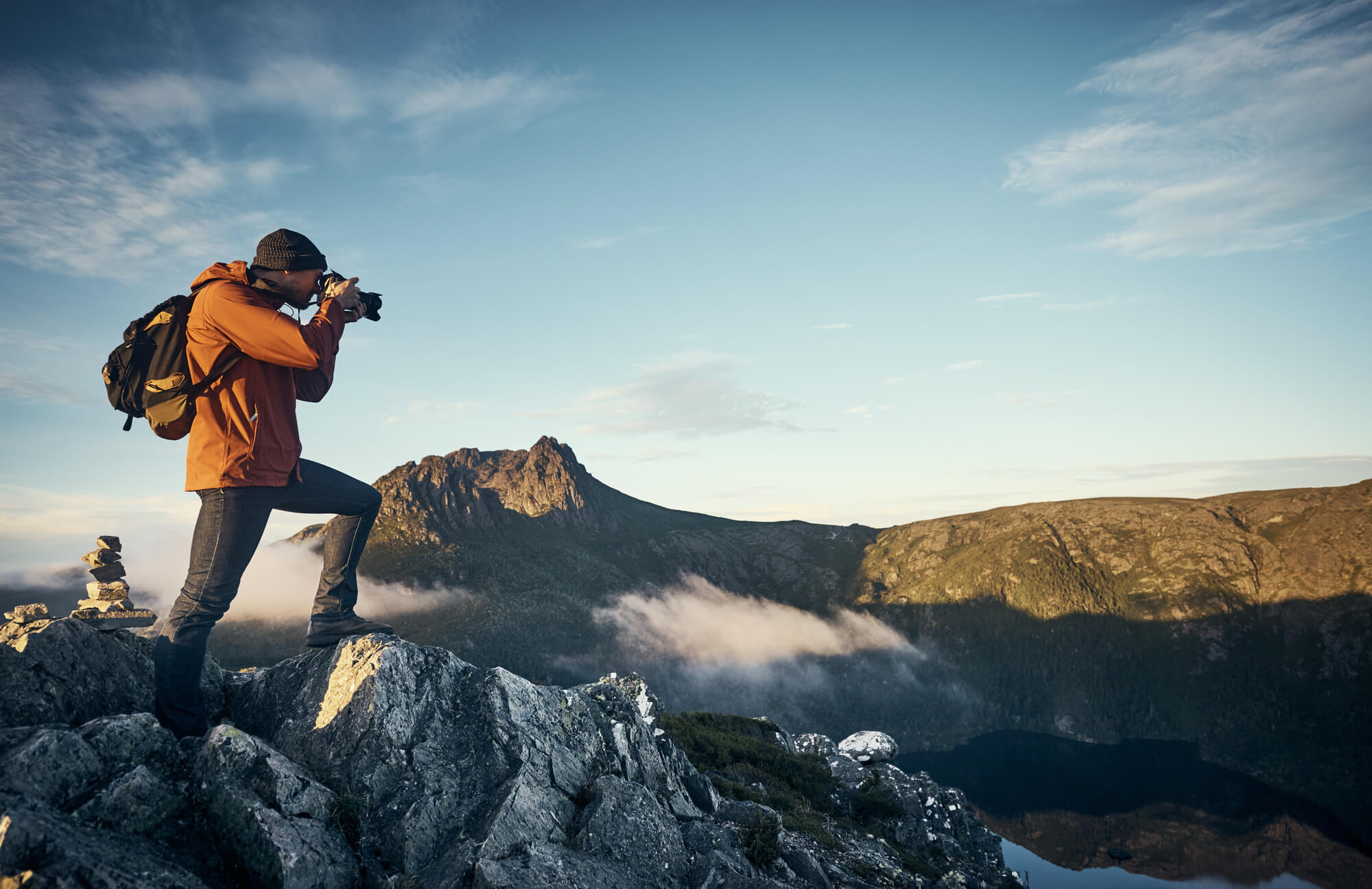 A man standing on top of a mountain taking a photograph