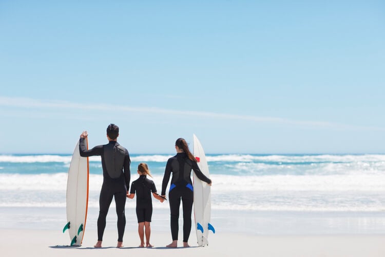 A family of three getting ready to surf