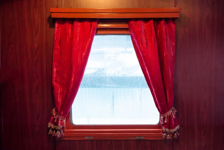 A train window with red velvet curtains