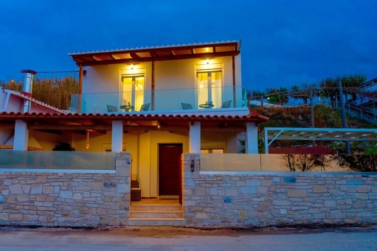 A lit up villa with balcony and stone walls