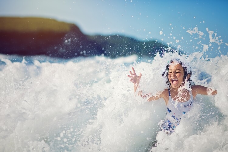 A young girl being splashed by waves in the sea