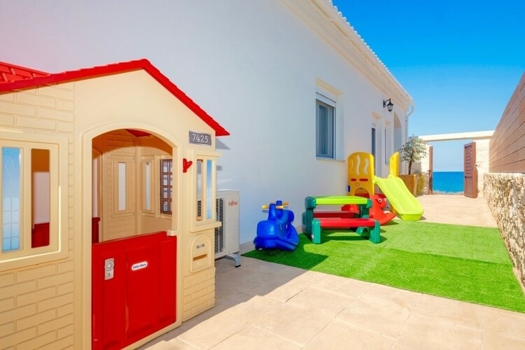 a villa with a children's playground and sea in the distance