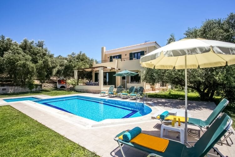 A villa with a pool and sun loungers