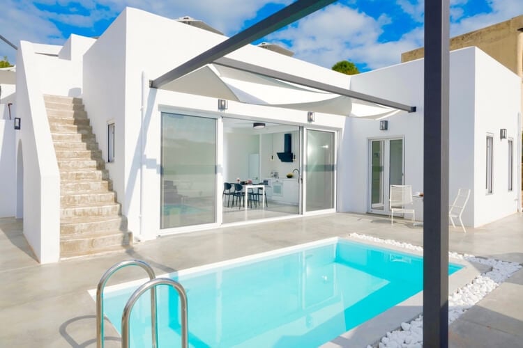 A small white villa with a pool in front