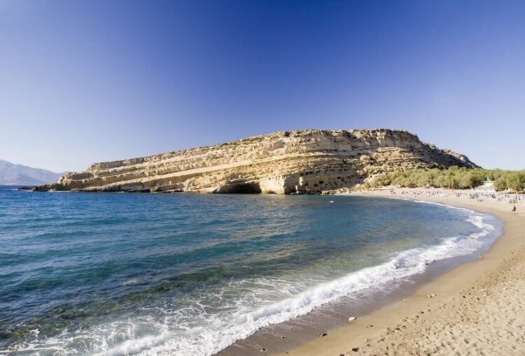 A beach with a cave formation in the background