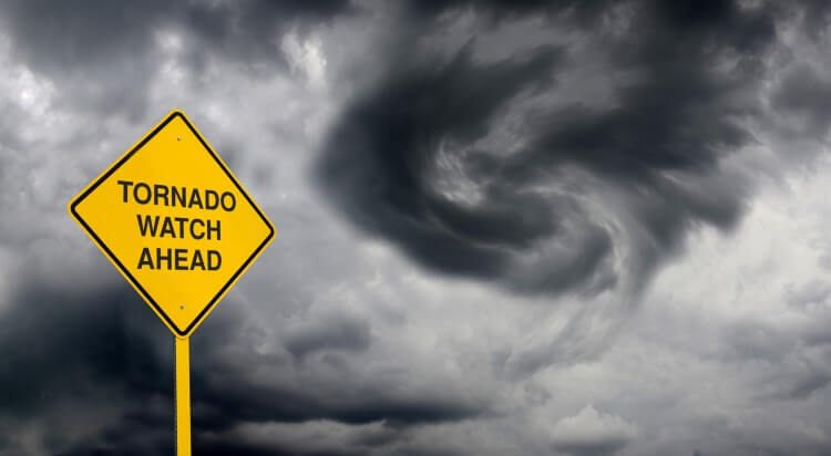 A tornado warning sign against a stormy sky