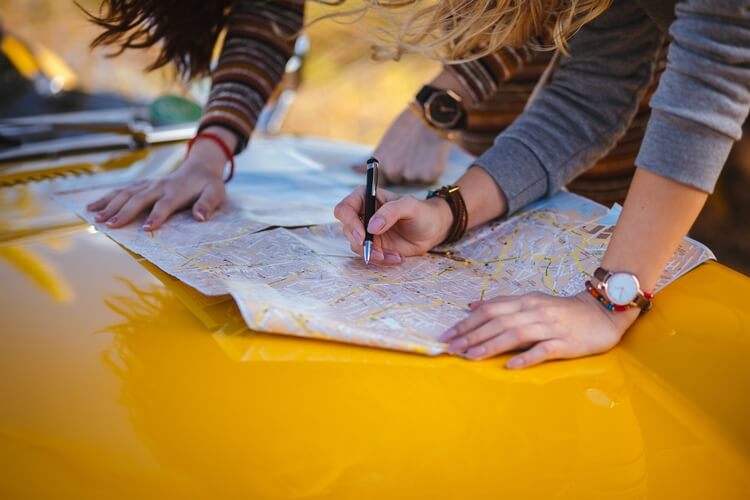 two people holding a map on a yellow car