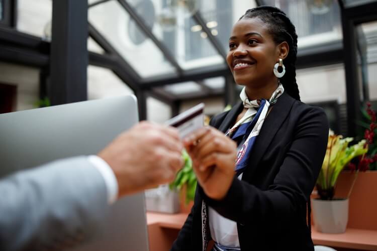 hotel receptionist handing over key card whilst smiling