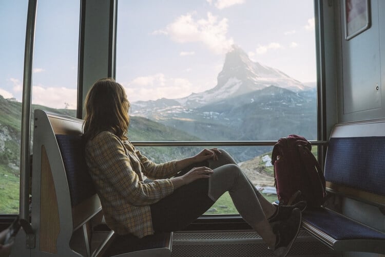 woman looking at mountain through train window