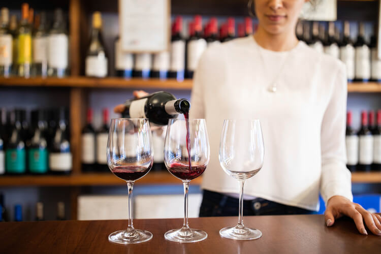 Bartender pouring red wine into glasses