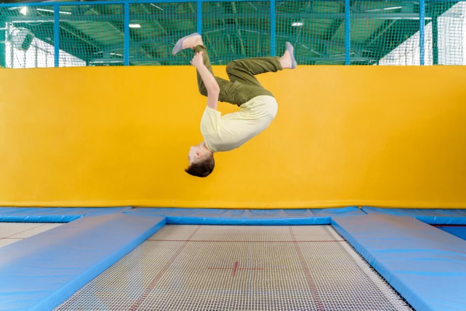 A teenage boy flipping on a trampoline