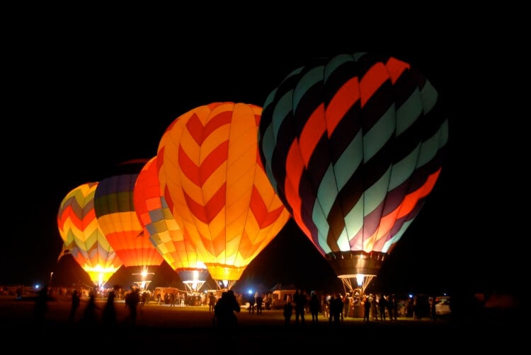 A showcase of glowing hot air balloons at night.