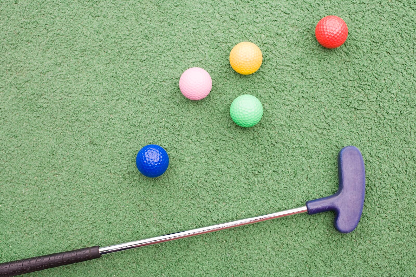 Mini golf putter and colorful balls.