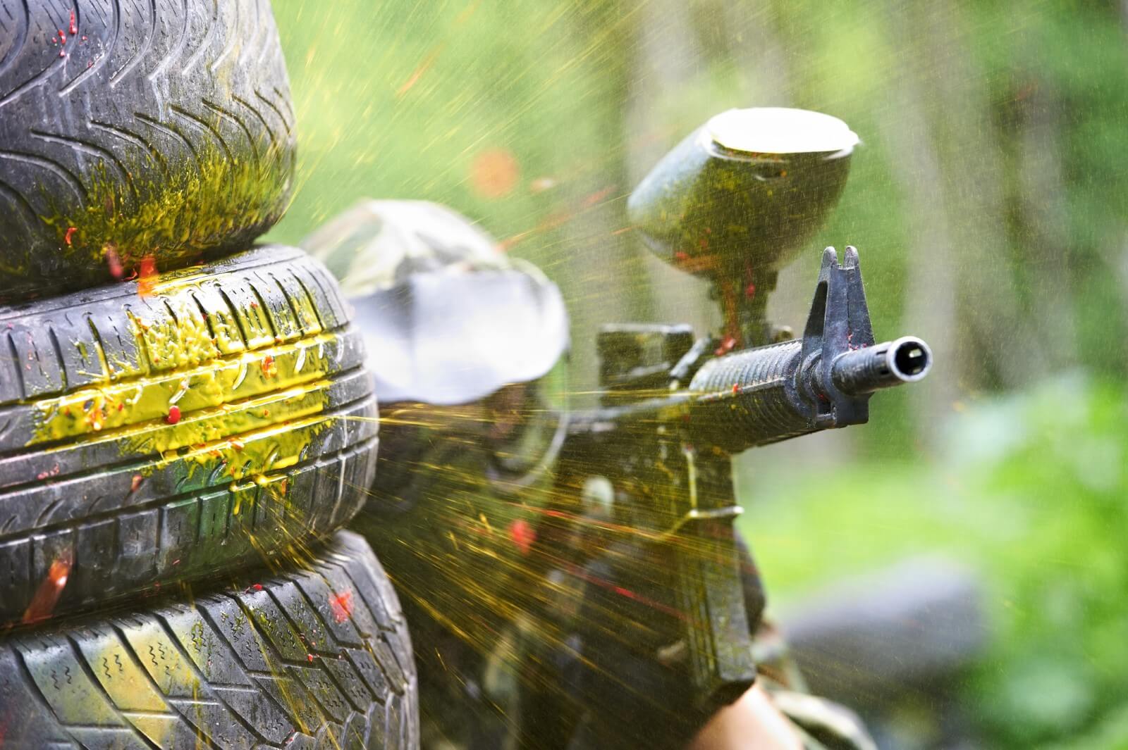 A paintball player taking aim and ducking for cover.