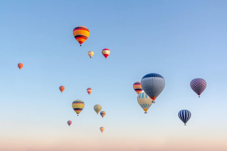 Multiple hot air balloons in a sunrise sky.