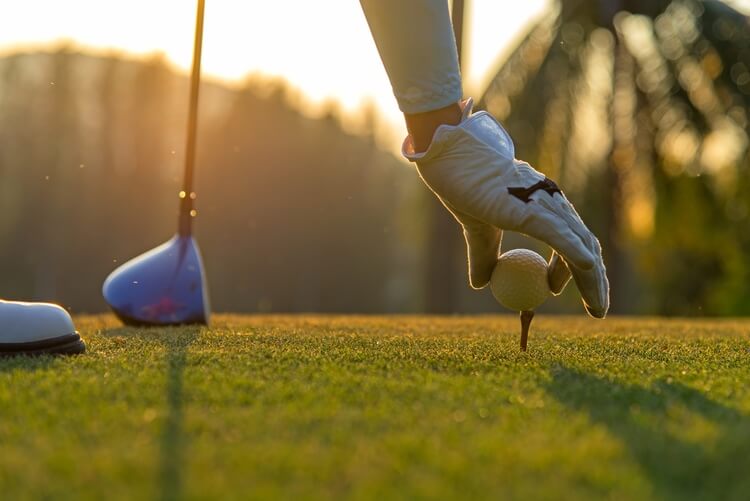 setting down a golf ball on a tee