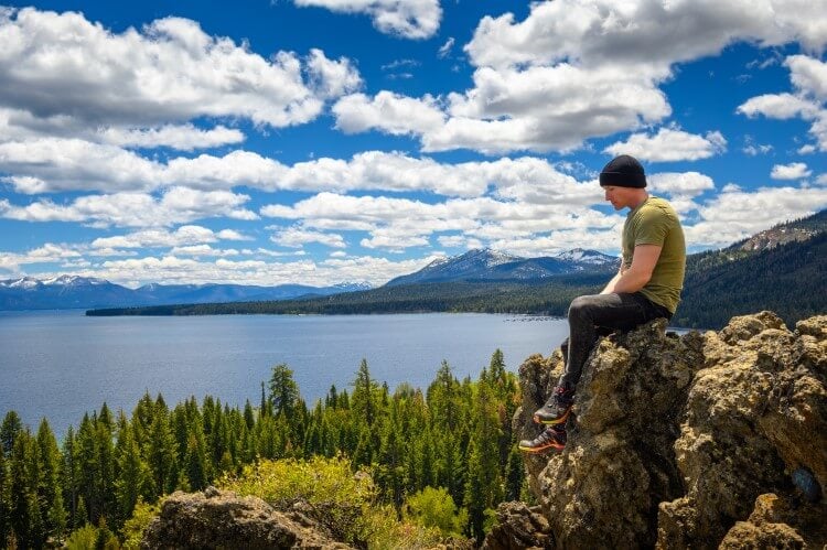 A man sitting on a rock overlooking a sunny Lake Tahoe