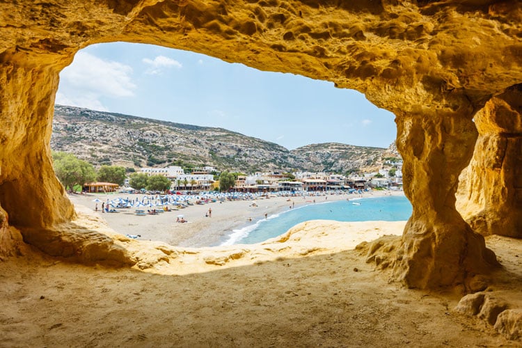 View of golden sand beach through a cave entrance in Crete - the best places to visit in April