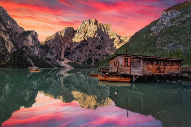 Pink sky over mountains and lake in the Dolomites - The best places to visit in August