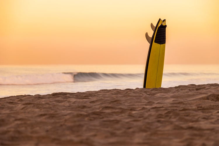 The best places to visit in December - surfboard sticking out of the sand