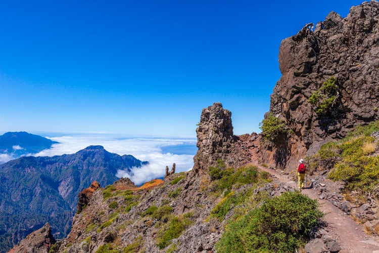 A person hiking along a mountain path above the clouds in the Canary Islands, one of the best places to hike in February
