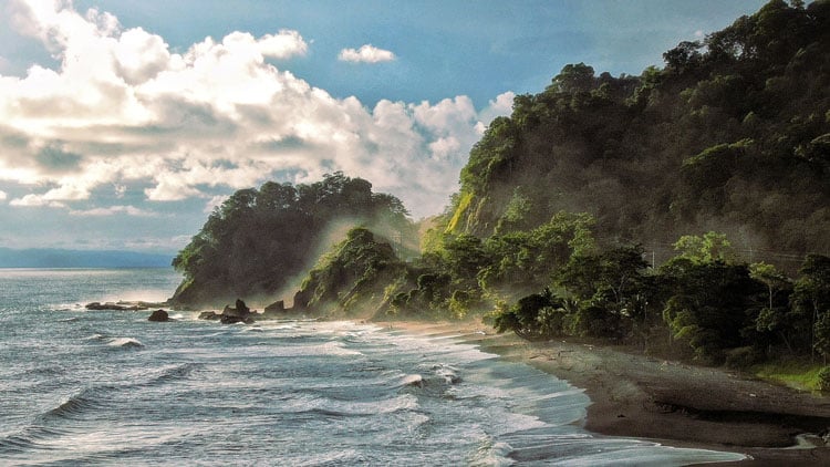 Costa Rica coastline with forest mountains and waves - one of the best places to surf in February