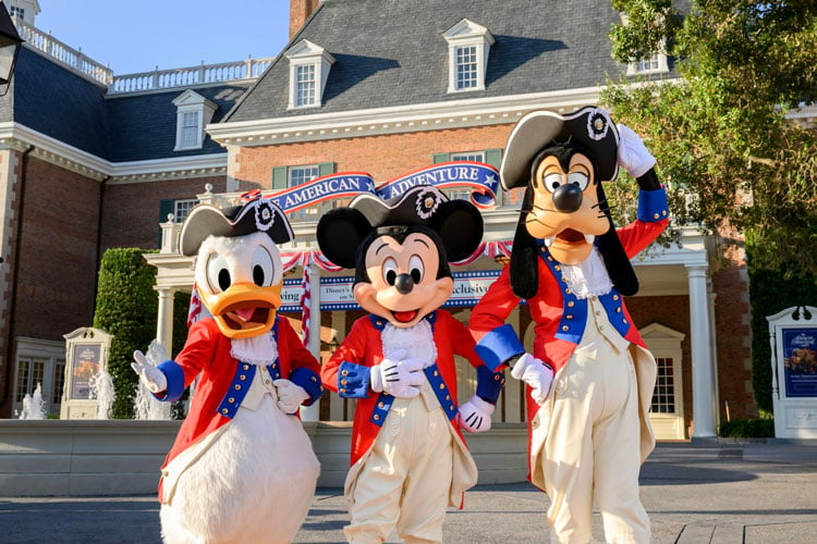 Three people dressed as Mickey Mouse, Goofy, and Donald Duck in Revolutionary uniforms at Disney World