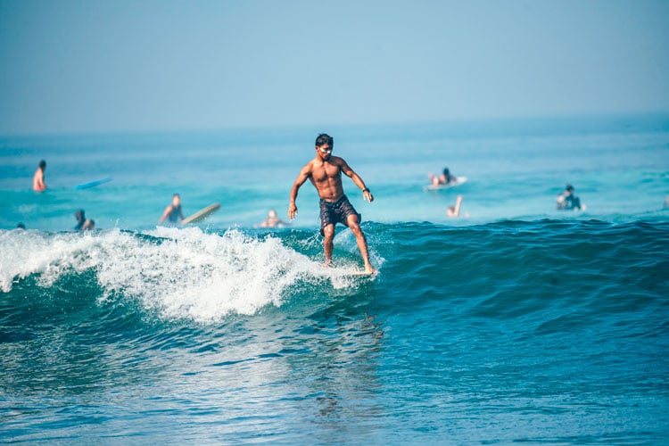 A person standing on a surfboard in Bali - best places to visit in March