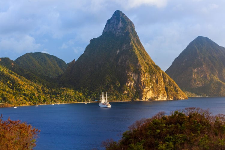 A sailboat in the sea i n front of one of the Pitons in Saint Lucia - best places to visit in March