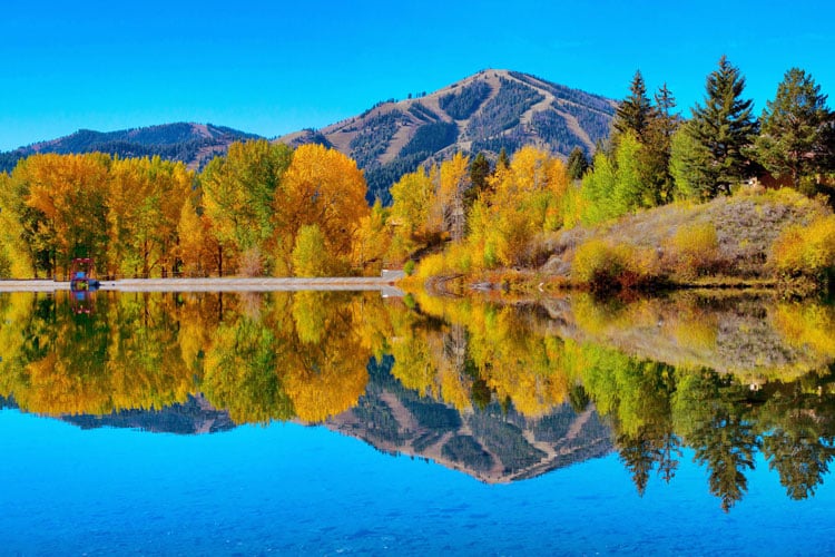 Reflections of a mountain and forest on a still lake in Idaho - the best places to visit in May