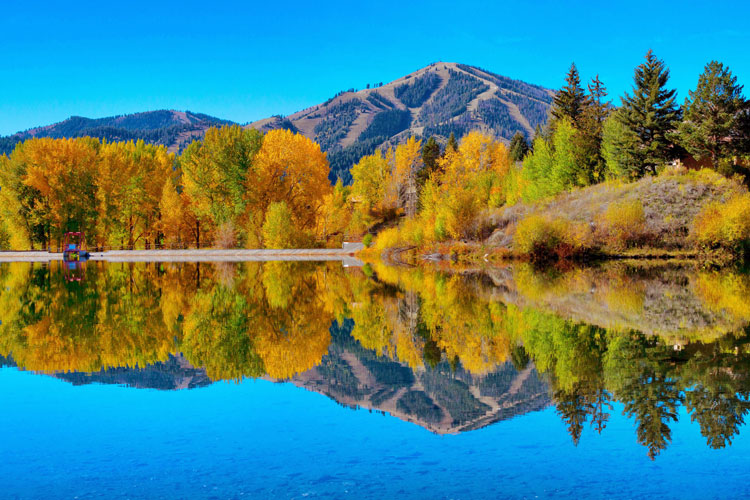 Reflections of a mountain and forest on a still lake in Idaho - the best places to visit in May