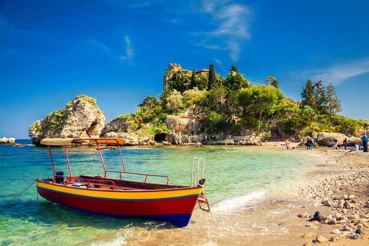 A fishing boat on a golden sand beach in Sicily - the best places to visit in May
