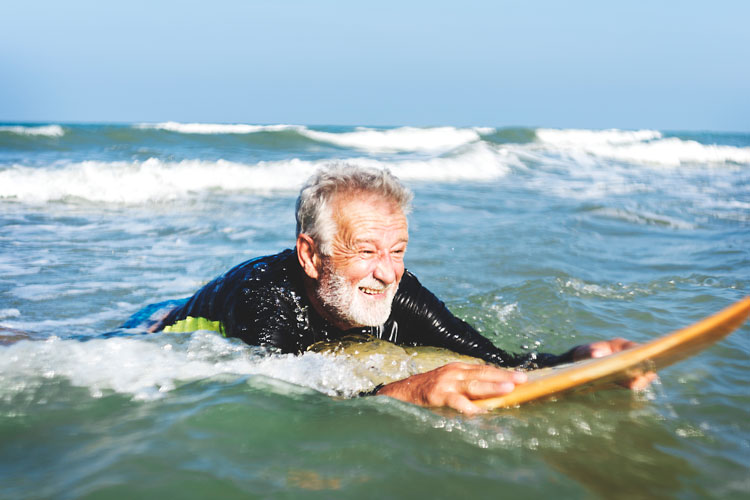 A man lying on a surfboard in the sea in Thailand - the best places to visit in May