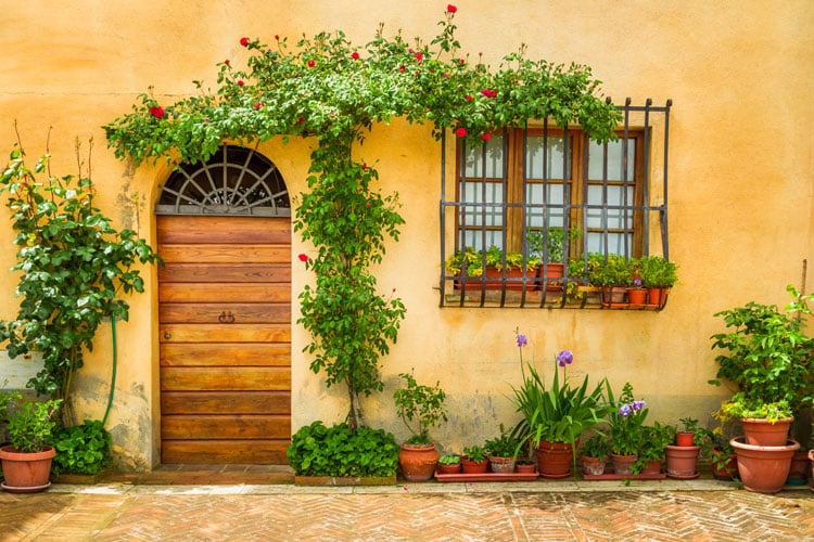 Yellow building with wooden door and vines around the edge in Tuscany - the best places to visit in May